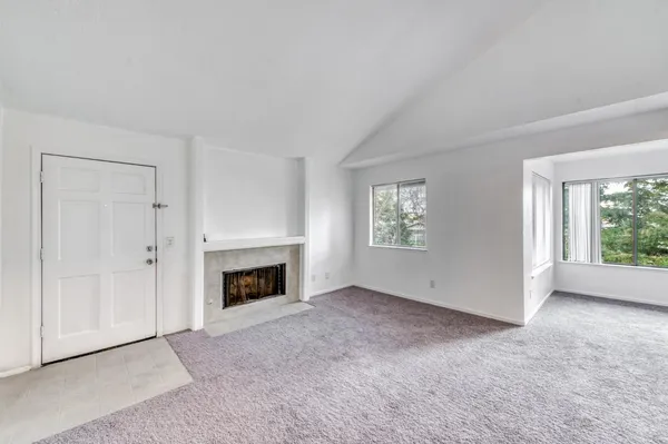 an empty room with windows and fireplace