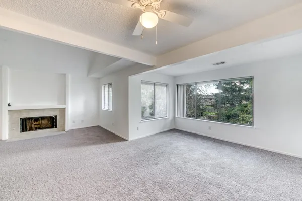 a view of an empty room with window and fire place