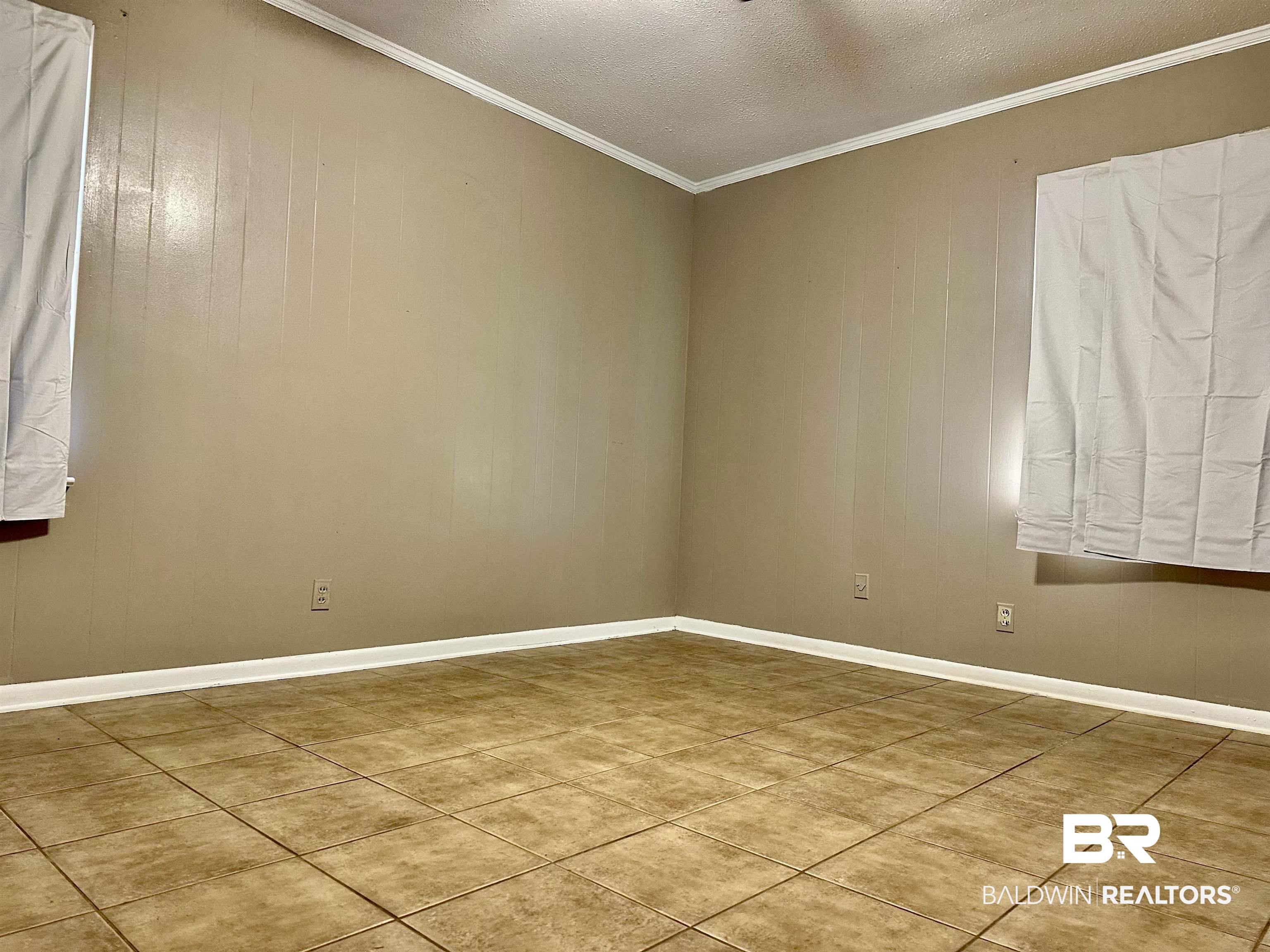 2664 Sowell Road Brewton, AL 36426 - Photo 9 of 12 Empty room featuring a textured ceiling, tile patterned floors, and crown molding