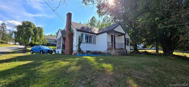 a view of a house with a big yard and large trees