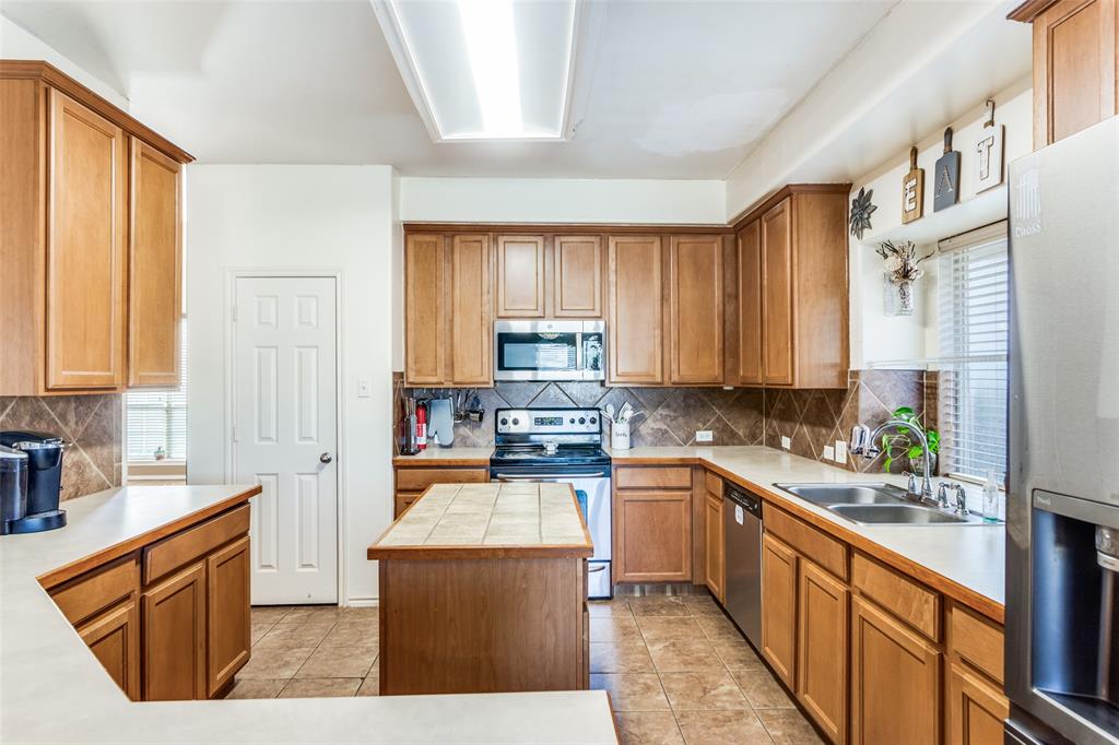 819 Hickory Street Burleson, TX 76028 - Photo 10 of 24 a kitchen with stainless steel appliances granite countertop wooden cabinets a sink and dishwasher a stove top oven with wooden floor