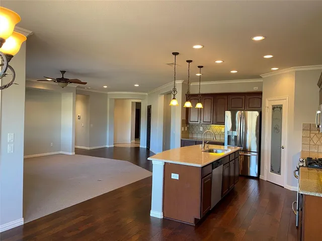 a large kitchen with stainless steel appliances kitchen island a large counter top and a chandelier