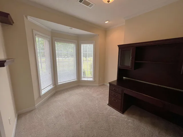 an empty room with chandelier fan and windows