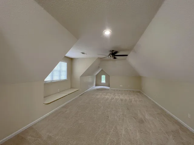 an empty room with ceiling fan and windows