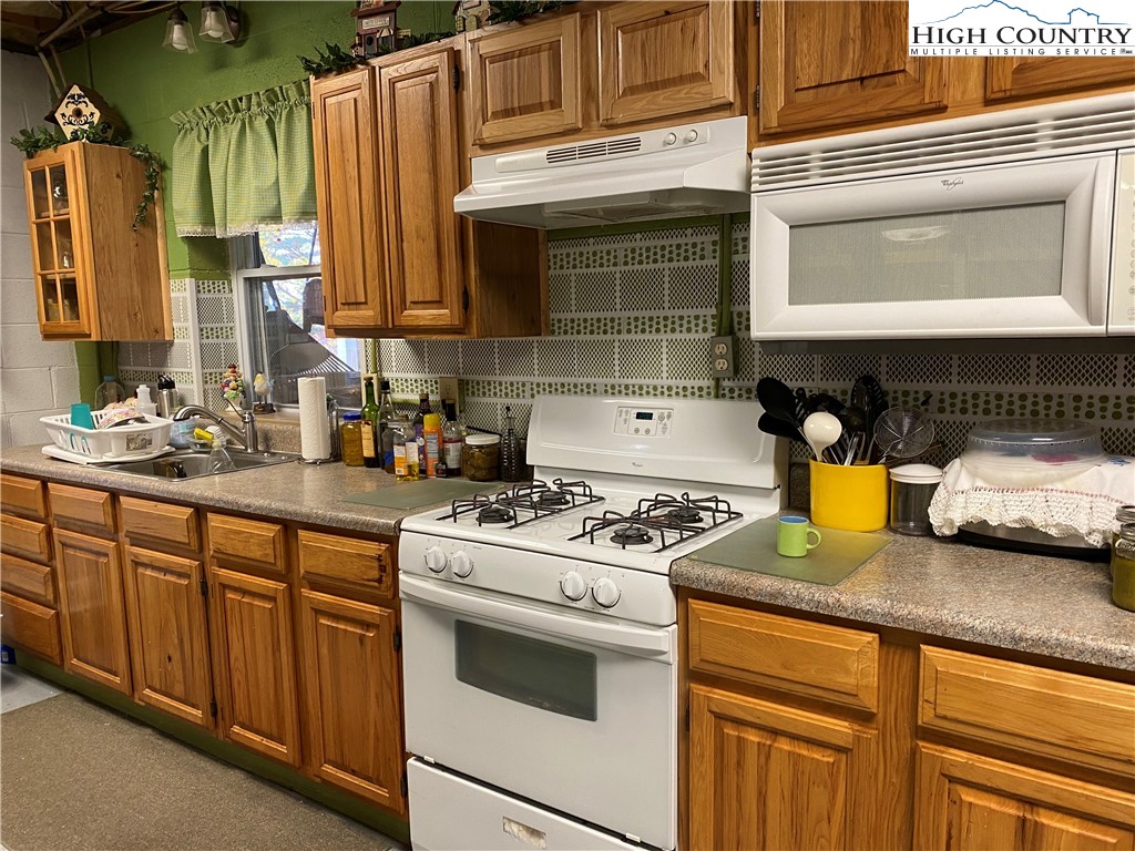 1241 Glade Creek School Road Ennice, NC 28623 - Photo 29 of 49 a kitchen with stainless steel appliances granite countertop a stove a sink and a microwave