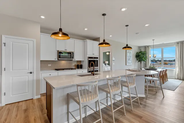 a kitchen with stainless steel appliances kitchen island granite countertop a table chairs and a view of living room
