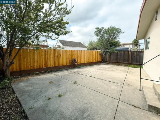 a view of backyard with large trees and wooden fence
