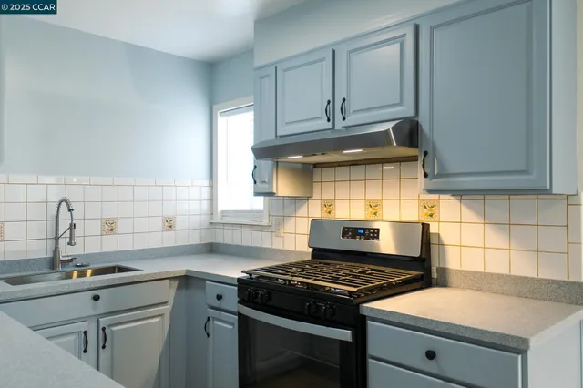 a kitchen with granite countertop a sink stove and cabinets