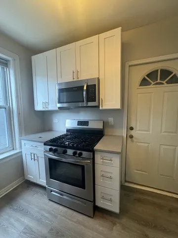 a kitchen with granite countertop cabinets stainless steel appliances and wooden floor