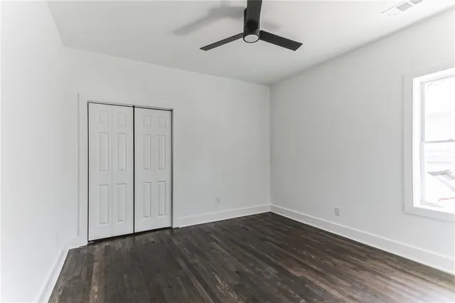 an empty room with wooden floor cabinet and windows