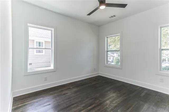 a view of an empty room with a window and wooden floor