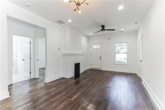 an empty room with wooden floor a ceiling fan and windows