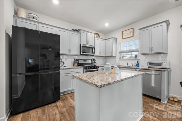 a kitchen with stainless steel appliances granite countertop a refrigerator a stove top oven a sink and dishwasher