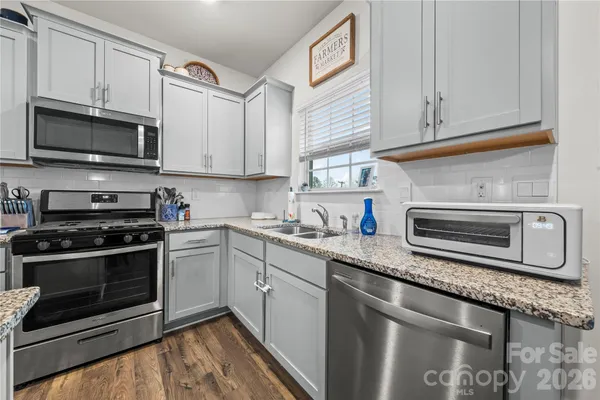 a kitchen with stainless steel appliances granite countertop a sink stove and microwave