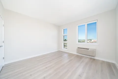 an empty room with wooden floor and windows