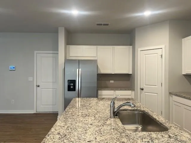 a kitchen with granite countertop white cabinets and a stove top oven