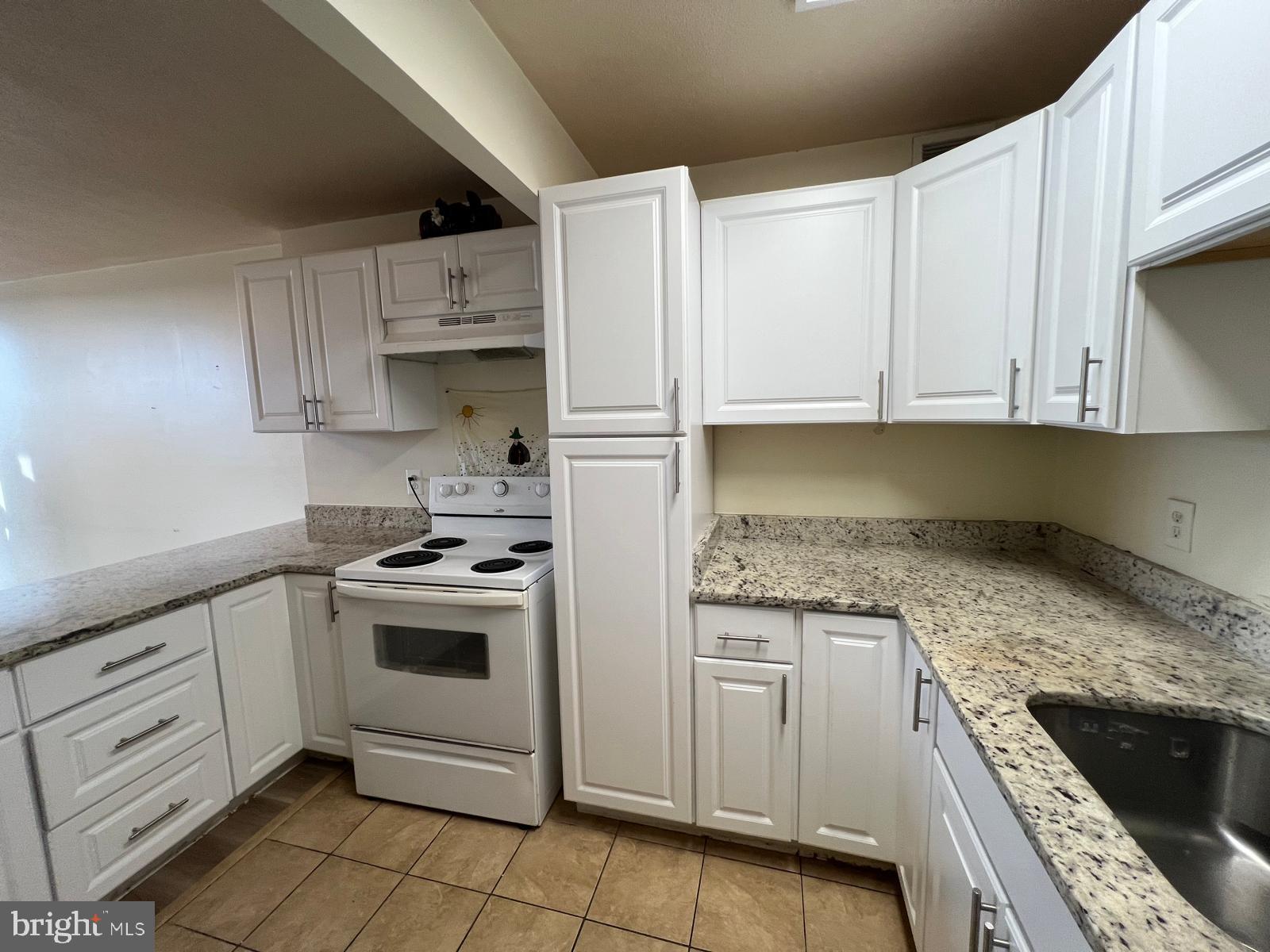 1836 Metzerott Road, Unit 916 Adelphi, MD 20783 - Photo 28 of 29 a kitchen with granite countertop white cabinets and white appliances
