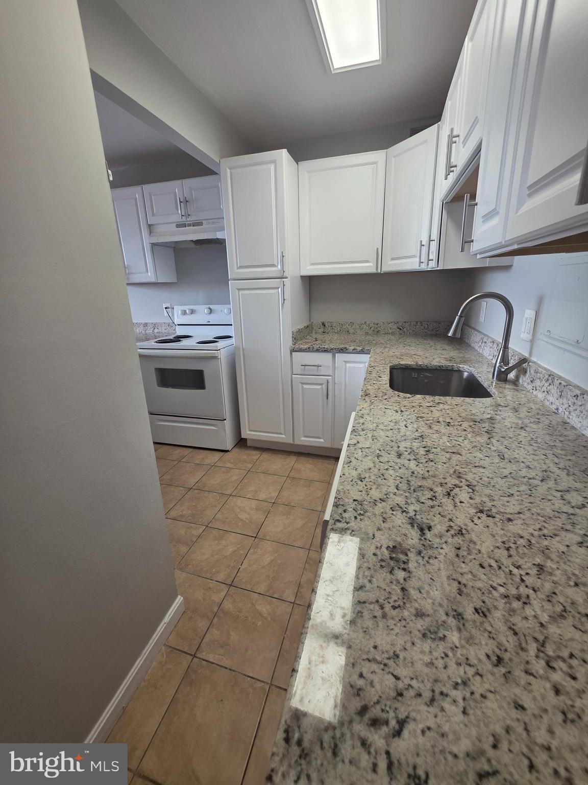 1836 Metzerott Road, Unit 916 Adelphi, MD 20783 - Photo 29 of 42 a kitchen with granite countertop a stove a sink and a microwave