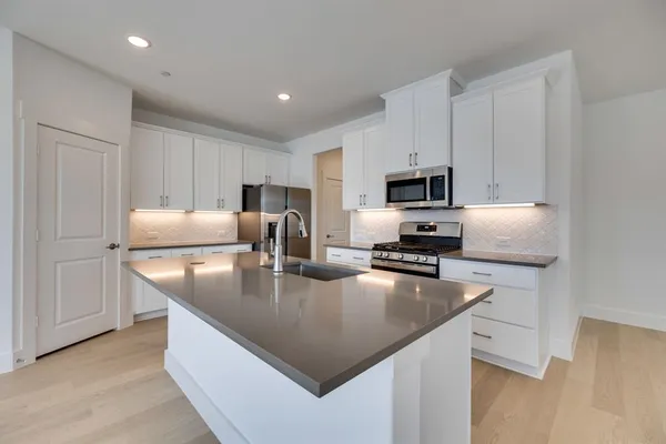 a kitchen with kitchen island white cabinets and stainless steel appliances
