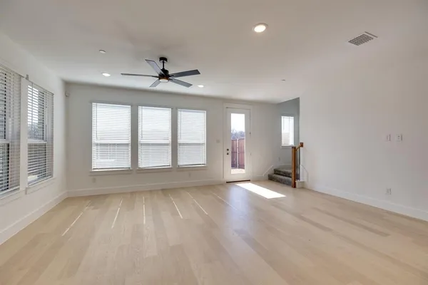 a view of an empty room with a window and wooden floor