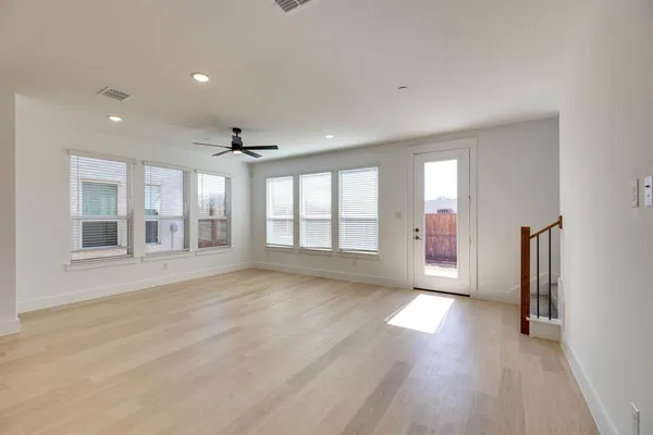 a view of an empty room with a window and wooden floor