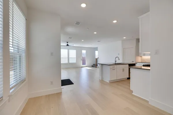 a view of a kitchen with kitchen island a sink wooden floor and a living room
