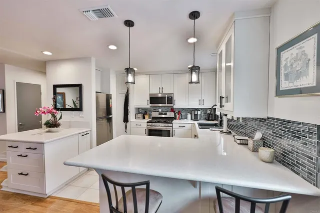 a kitchen with stainless steel appliances kitchen island granite countertop a stove a sink a oven a dining table and chairs