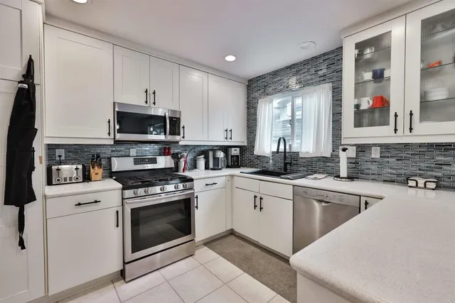 a kitchen with white cabinets stainless steel appliances and sink