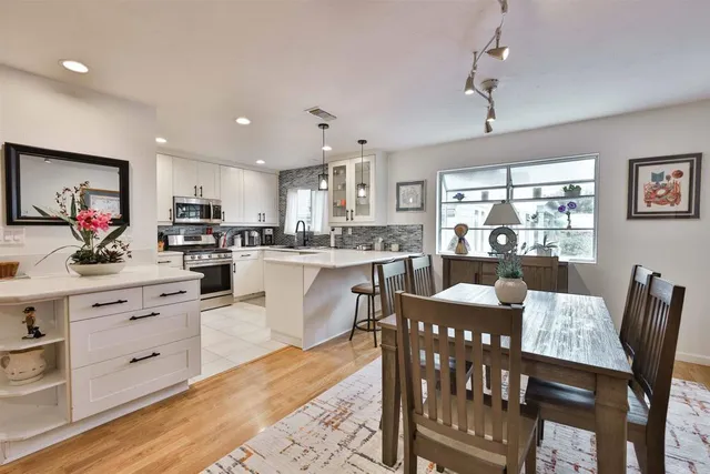 a kitchen with stainless steel appliances kitchen island granite countertop a table chairs and a refrigerator