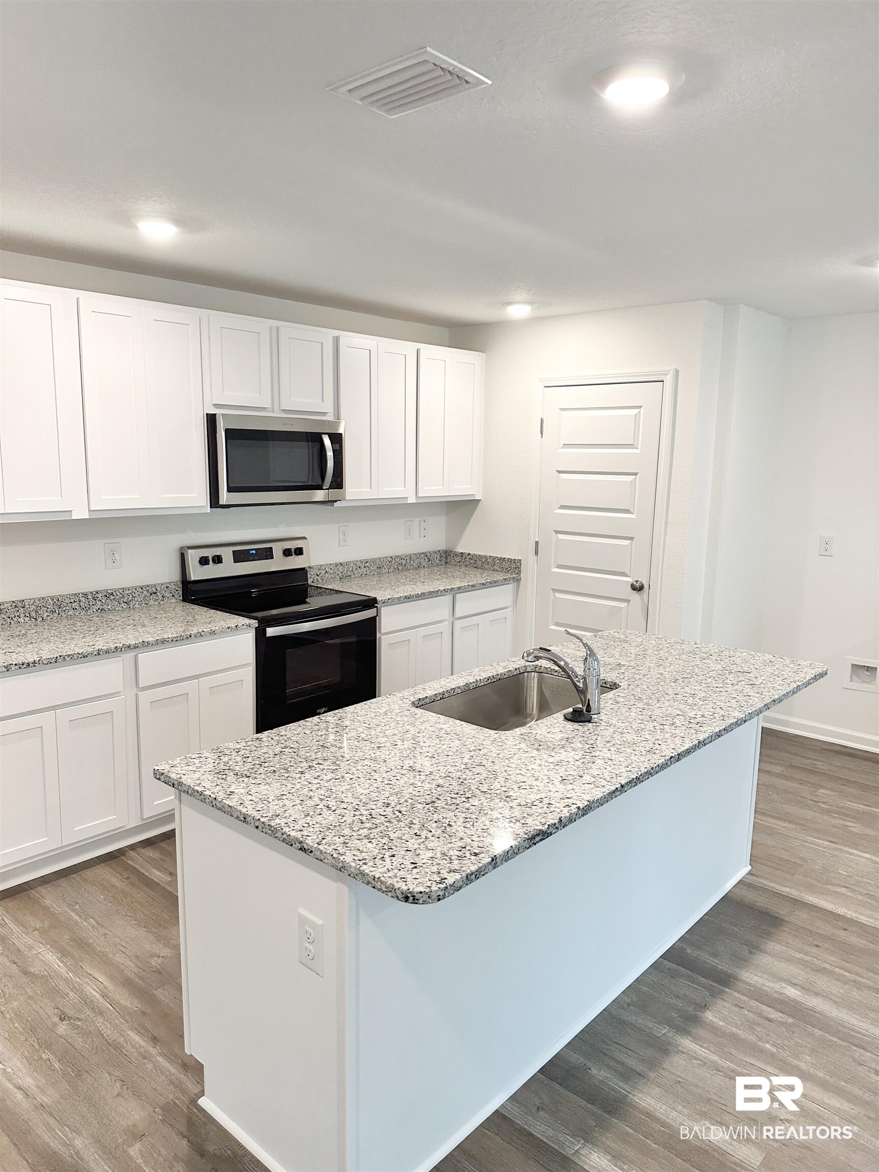 22275 Aleutian Avenue Foley, AL 36535 - Photo 5 of 72 Kitchen with white cabinetry, an island with sink, appliances with stainless steel finishes, hardwood / wood-style flooring, and sink