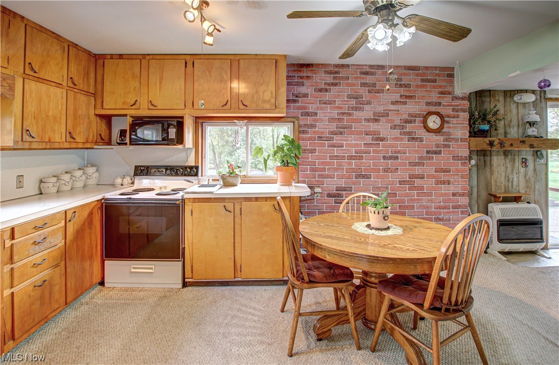 3946 Poe Road Medina, OH 44256 - Photo 3 of 35 Kitchen with brown cabinets, light countertops, white electric range, light carpet, and brick wall