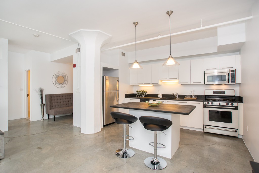 a kitchen with stainless steel appliances granite countertop a stove a sink a refrigerator and chairs