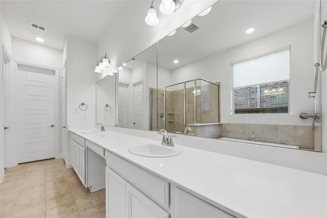 a spacious bathroom with a sink a vanity a mirror a bathtub and shower