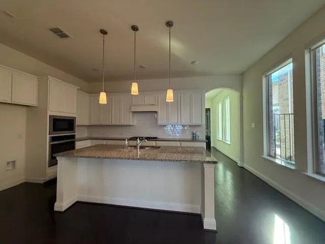a kitchen with stainless steel appliances granite countertop a sink a stove and a wooden floors