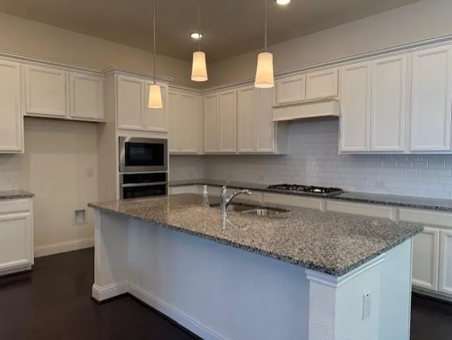 a kitchen with granite countertop a sink a stove and cabinets