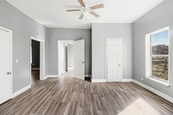 a view of empty room with wooden floor and fan