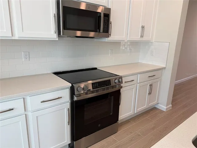 a kitchen with stainless steel appliances white cabinets and a stove top oven