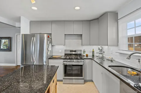 a kitchen with granite countertop kitchen island stainless steel appliances a refrigerator a stove a sink a center island and windows