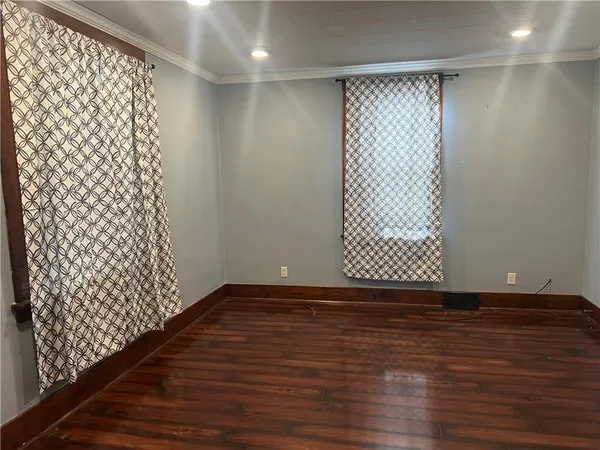 a view of an empty room with wooden floor and a shower curtain