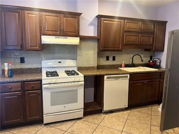 a kitchen with stainless steel appliances granite countertop a stove a sink and a microwave