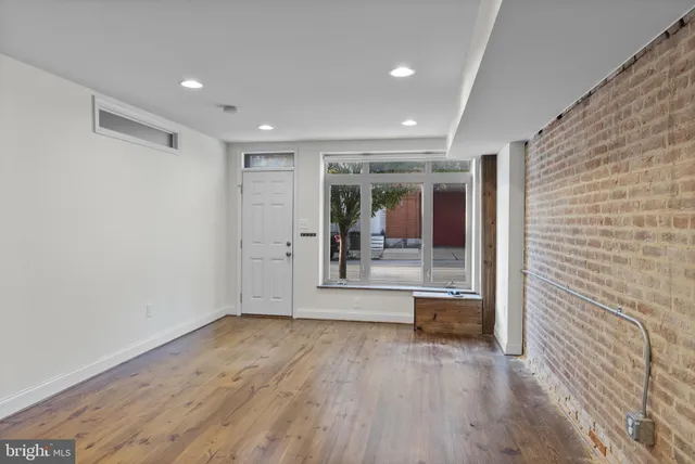 a view of a hallway with wooden floor and a living room