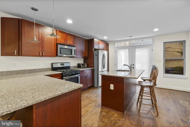 a kitchen with stainless steel appliances granite countertop a refrigerator a stove top oven a sink dishwasher and wooden cabinets