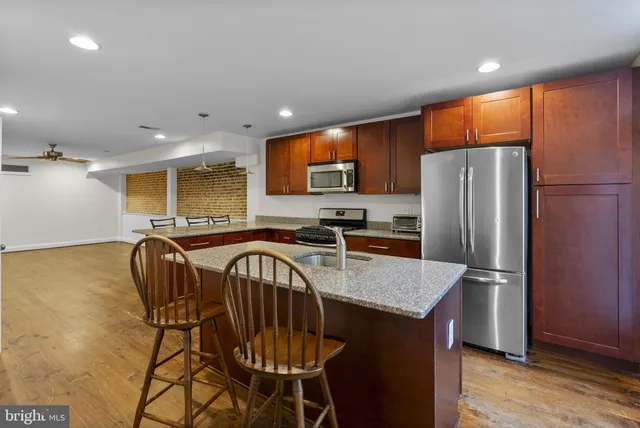 a kitchen with stainless steel appliances granite countertop a refrigerator a sink a stove a dining table and chairs