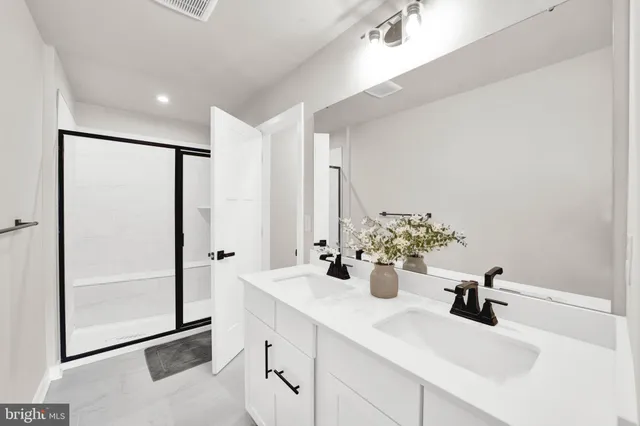 a bathroom with a double vanity sink mirror and shower
