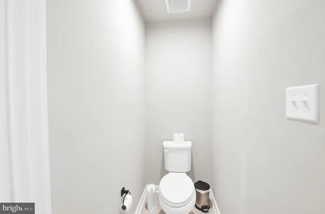 a white toilet sitting next to a white wall
