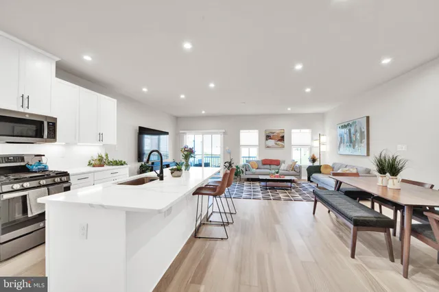 a view of a kitchen with kitchen island a large counter top space a center island stainless steel appliances and a dining table view