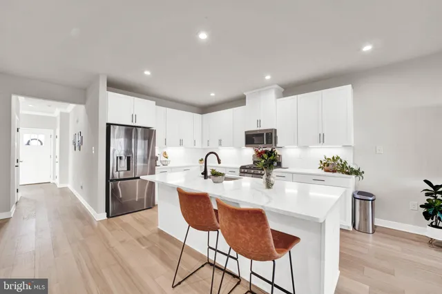 a kitchen with stainless steel appliances a refrigerator a stove a sink a dining table and chairs