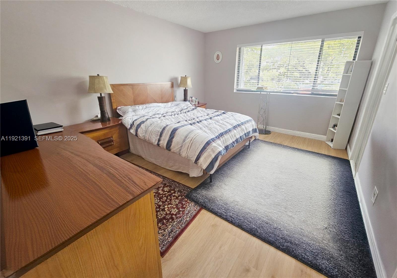 10700 Northwest 7th Street, Unit 5A Miami, FL 33172 - Photo 12 of 20 a bedroom with a bed and wooden floor