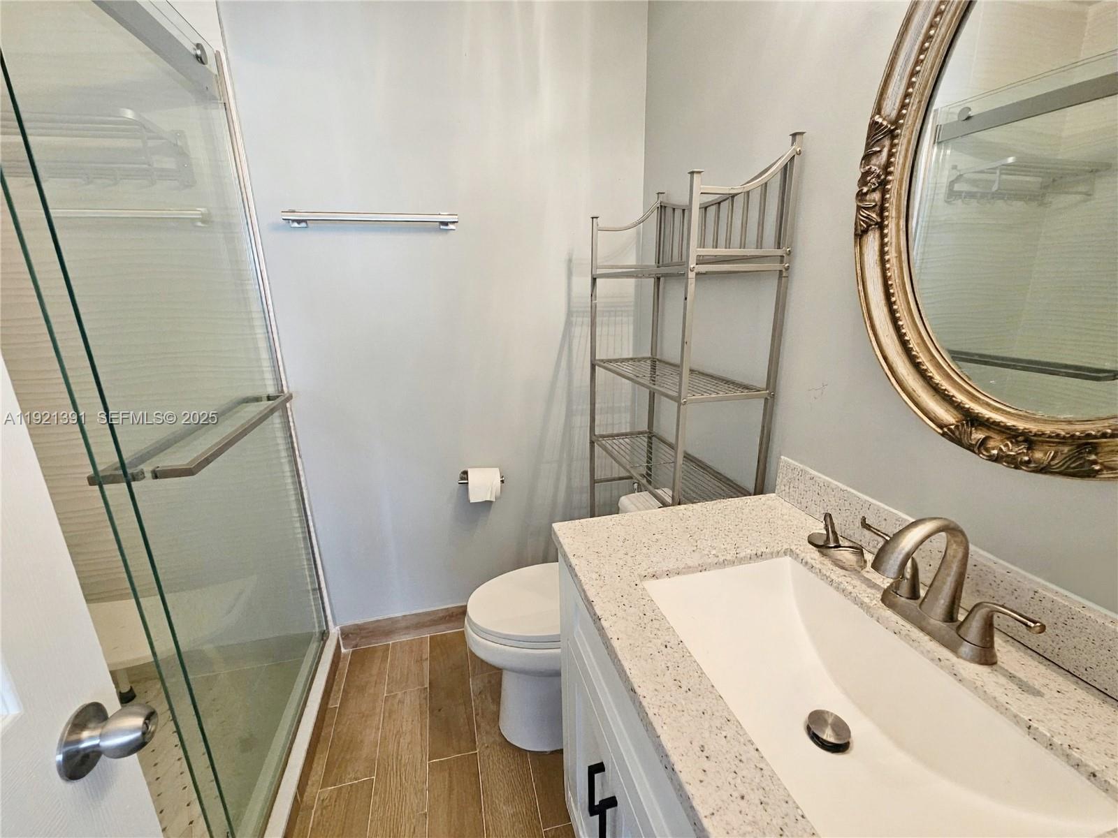 10700 Northwest 7th Street, Unit 5A Miami, FL 33172 - Photo 18 of 20 a bathroom with a sink a toilet and a mirror