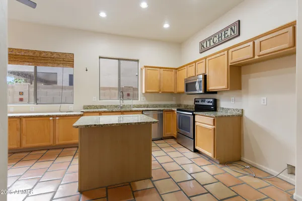 a large kitchen with granite countertop a stove a sink and a refrigerator